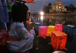 Japanese children in summer kimono offer prayers with paper lanterns