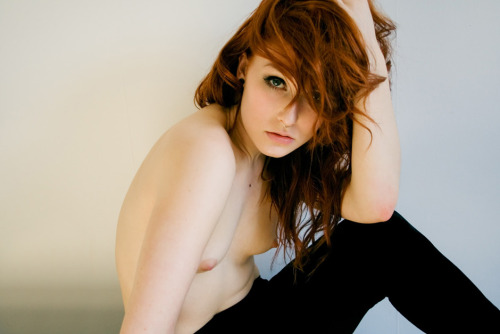 Gorgeous topless redhead in black stretchy pants.