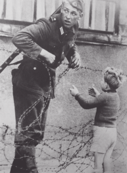 swinq:lmprovident: An East German soldier helping a boy cross