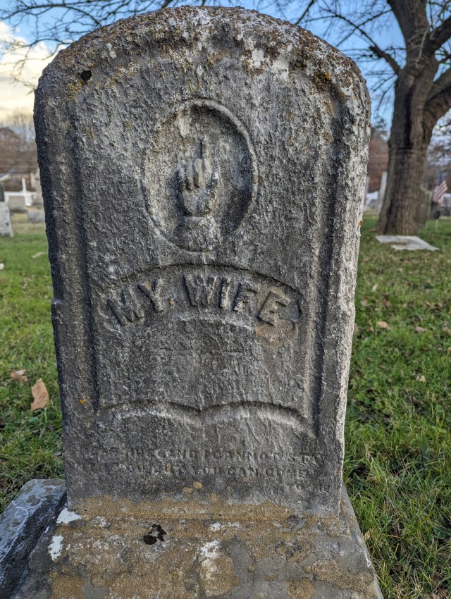 a 19th century tombstone in Avon, Connecticut, bearing the faded legend, my wife, with a hand pointing upwards.