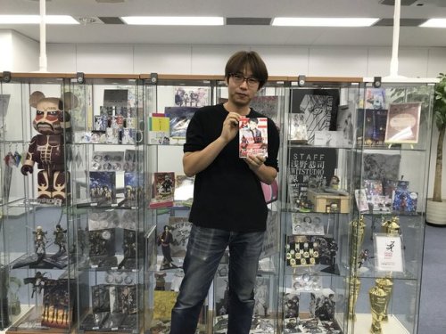 Hanamura Yaso, the author of the anime production manga, ANIMETA! (Animator!), shares photos of SnK Animation Director Asano Kyoji after meeting him at WIT Studio! Asano is posing in front of the merch display, which has plenty of SnK items.More on