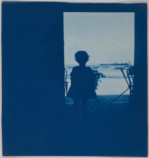 Child standing in the doorway of a seashore house, ca. 1900