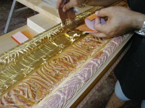 This reproduction of a 19th century frame was carved entirely by hand. The moulding is 12 inches wide and is finished in 22k gold leaf over yellow clay with red highlights. The pictures above show some of the steps during production.