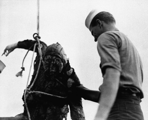 American sailor examining the charred corpse of a Japanese pilot hauled from the bottom of Pearl Har