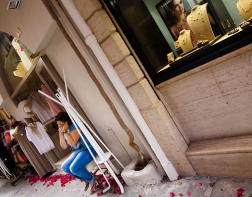 Phone conversation outside the clothes shop. Αραμπατζόγλου, Rethymno, Crete.