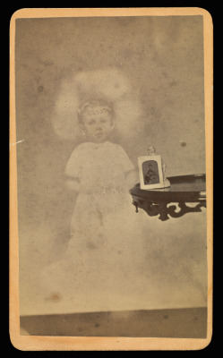 visionsofour-past: • Child “spirit” with photograph and figurine on table. Artist/Maker: William H. Mumler (American, 1832 - 1884) Place of origin:  Boston, Massachusetts, United States  Date: 1862 - 1875 Medium: Albumen silver print