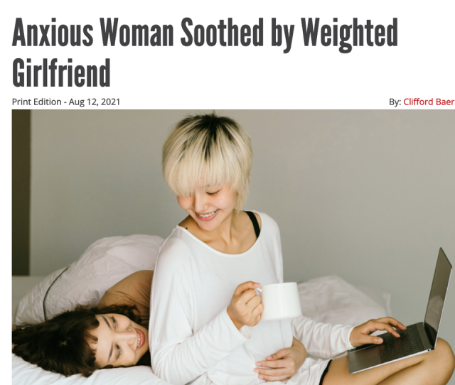 Headline that reads "Anxious Woman Soothed by Weighted Girlfriend". Below is a photo of two women on a bed smiling, one laying down with her arm around the other who's sitting with a laptop and cup.