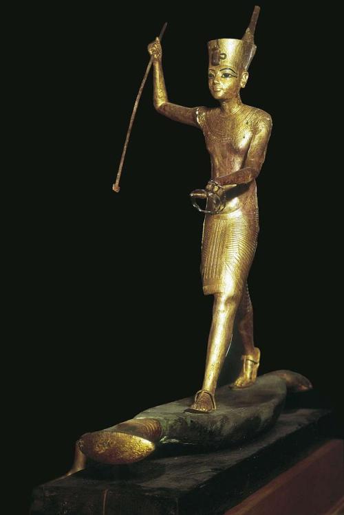 Statuette of Tutankhamun the HarpoonerA gilded, wooden statuette of King Tutankhamun stands on a woo