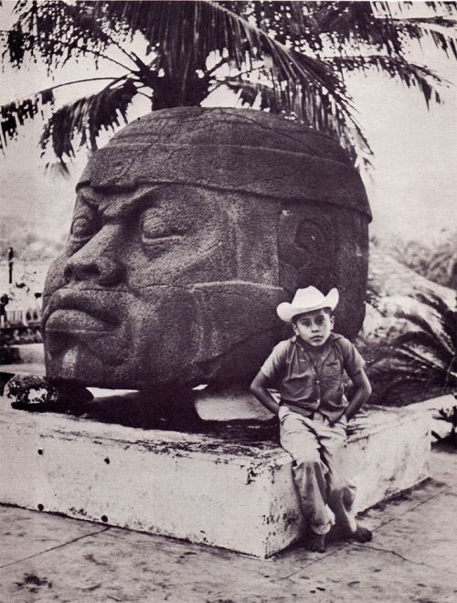 archaeoart:Mexican boy in front of Olmec head, Mexico, date unknown.