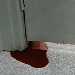 blood leaking out from the bottom of a bathroom stall