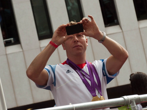 Sir Chris Hoy photographs the crowd during the Our Greatest Team parade after London 2012 (by Sherif