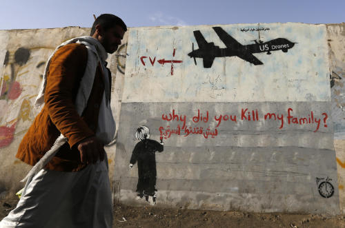 mvtionl3ss:   A man walks past a graffiti, denouncing strikes by U.S. drones in Yemen, painted on a 