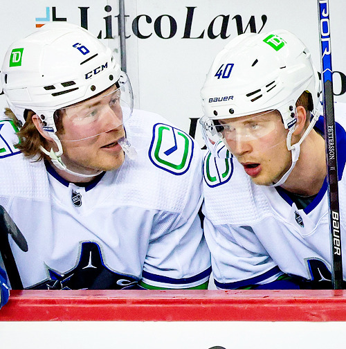 Brock Boeser and center Elias Pettersson talk on the bench in a game against the Calgary Flames (Apr