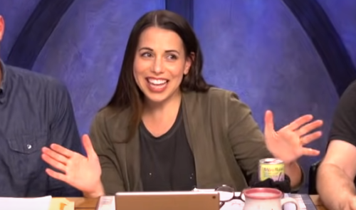 a screenshot of Laura Bailey in character as Jester Lavorre, a big grin on her face and hands in an exuberant 'jazz hands' posture