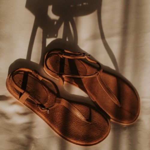 No feet but great shot of leather sandals casting shadows.