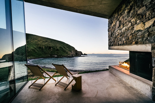 archatlas:    Seascape Retreat    Patterson AssociatesA romantic beachside cottage is set into a rock escarpment in a tiny boulder strewn South Pacific cove. It is a shelter designed as a honeymoon retreat for paying guests consisting of just three rooms,