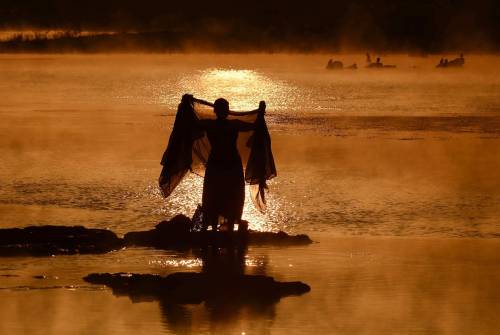 fotojournalismus:A woman washes a sari in the Narmada River at sunrise on a foggy winter morning in 