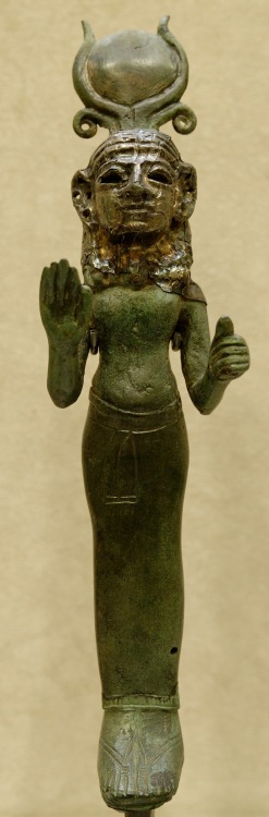 dwellerinthelibrary:A Phoenician goddess, wearing a Hathor-style headdress, raises a hand in a gestu