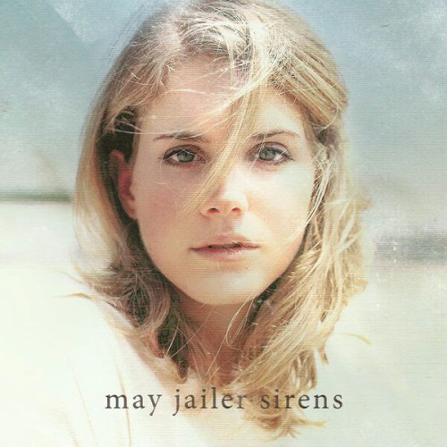 Young Lana Del Rey (going by the name May Jailer) on the center of the cover of her album Sirens. She looks forward, her blonde hair falls over her face and the beach is behind her.