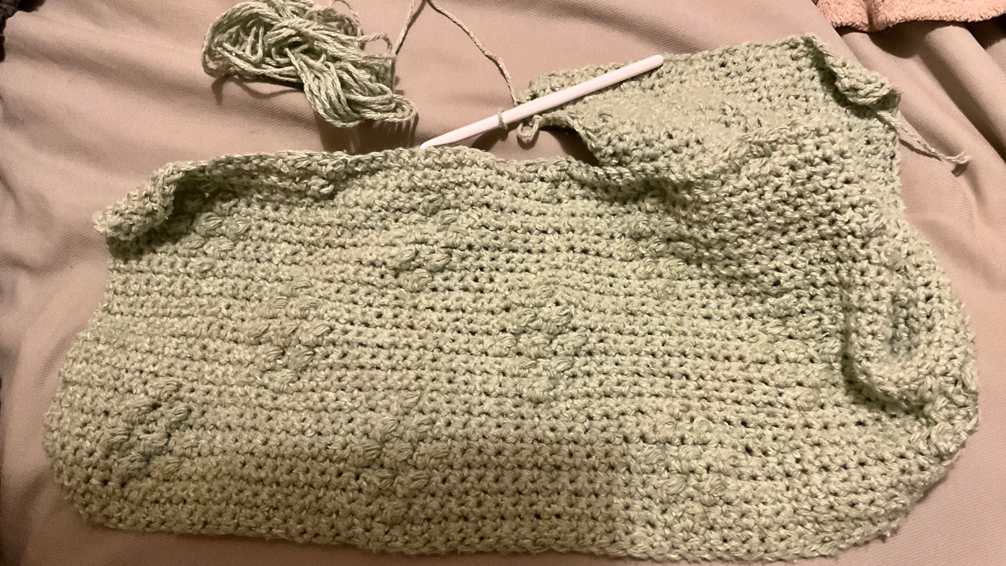 The light green blanket in progress, now showing three completed lines of diamond shapes. The skein of yarn attached to it is down to just a small handful.