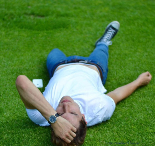 an one-legged guy in jeans and converse sneaker lies alone on the lawn and is waiting for help from 