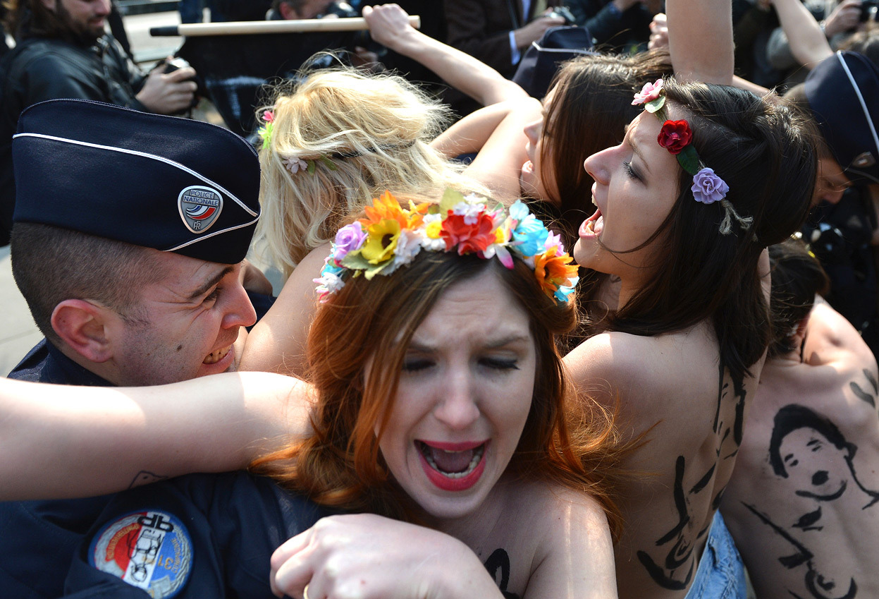 From Femen Stages a ‘Topless Jihad’, one of 31 photos. Here, activists of the women’s rights movement Femen face riot policemen during a topless protest near Tunisia’s Embassy in Paris, on April 4, 2013. Femen called for a day of international...