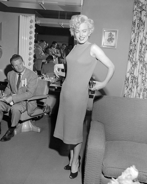 Marilyn Monroe / removing the belt of her dress as she meets with reporters in her dressing room on 