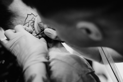 Black and white stock image of tattoo artist tattooing a design on skin. From freestock.org.