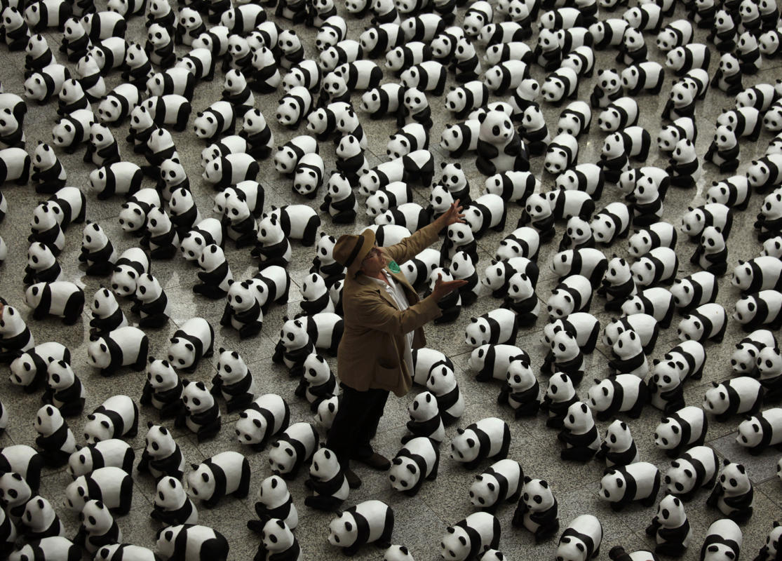 French artist Paulo Grangeon throws one of his paper mache pandas displayed as part of an art installation at the Hong Kong airport (Photo by Bobby Yip/Reuters via Yahoo News)