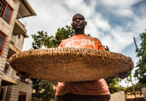 A winnowing Basket held upfront by Mugisha Bernard as he poses for a photograph. 2021 Photo by : ©JO