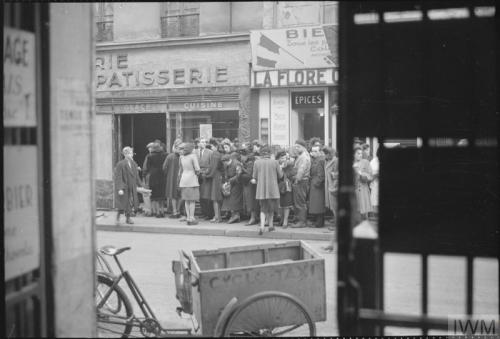 Everyday life in liberated Paris (spring 1945):A large group of civilians queueing outside a bakery-