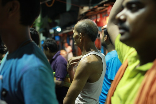 An anxious crowd gathers around one tiny television screen to catch the final minutes of the India -