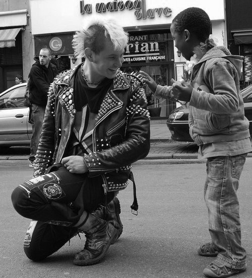  A punk stops during a gay pride parade to allow a mesmerized child to touch his jacket spikes. 