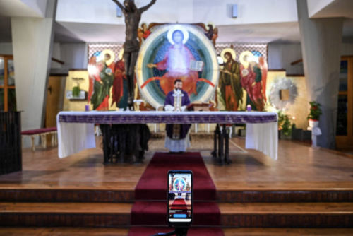 Don Piero Belluso is live-streaming the Mass through his mobile phone, in a deserted church, March 2