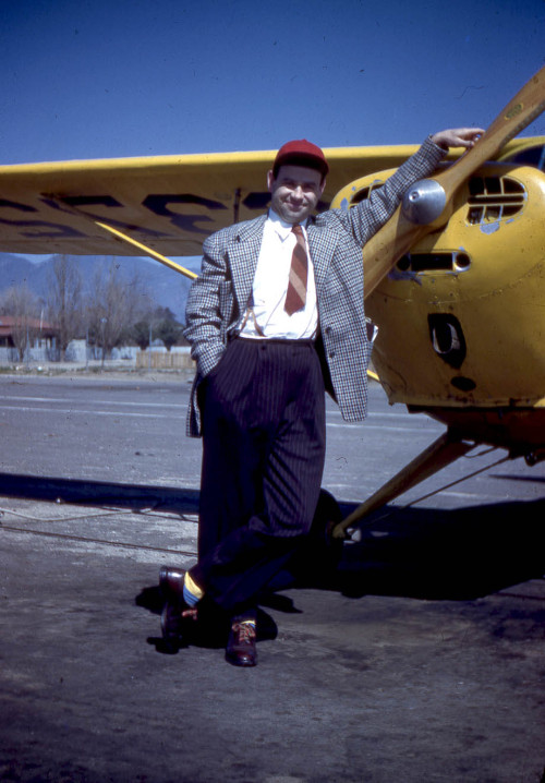 Pilot gear: plaid sportsjacket, diagonal striped tie, accent socks, and a red cap.
