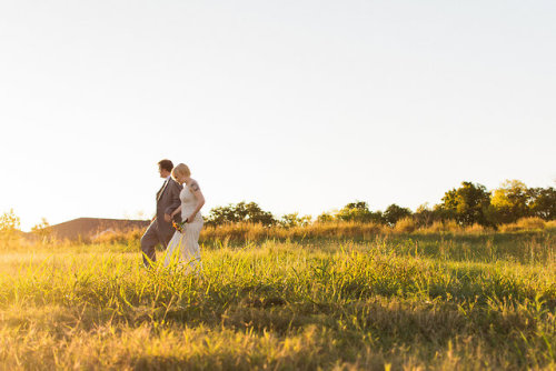 (image description: a photo of a person in a gray suit and a person in a white gown walking through 