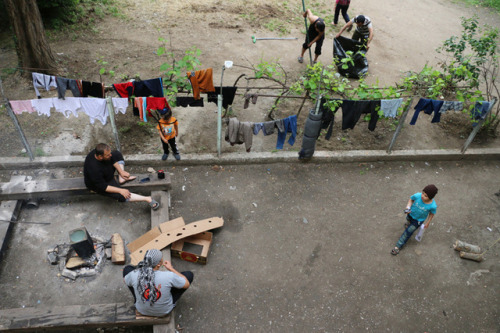 Refugees sit in front of an abandoned house at the railway station of Idomeni. May 2016