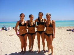 sexywithorwithout:  Four hot tan friends hanging out on the beach in matching black bikinis.