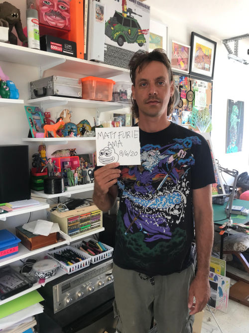 Matt Furie stands holding a picture of Pepe for a reddit AMA