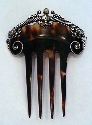 This is a Romanov comb. It is tortoiseshell, with a gold, silver, and pearl heading and the mark of 