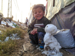 levantineviper:  imagine-whats-unimaginable:  BEKAA VALLEY, LEBANON: The little Syrian boy sits proudly next to his snowman and smiles for CNN’s Christian Streib. He has no coat, gloves or hat to protect him from the freezing cold, but for a moment