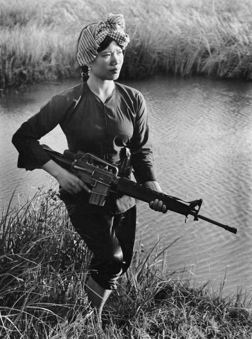 historicaltimes: Female Vietcong guerilla fighter carrying a m-16 rifle during the Vietnam war in 19