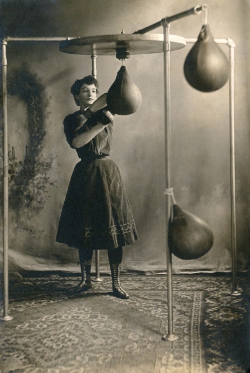 back-then: A young woman working out with boxing gloves and a punching bag, 1890 Underwood Archives