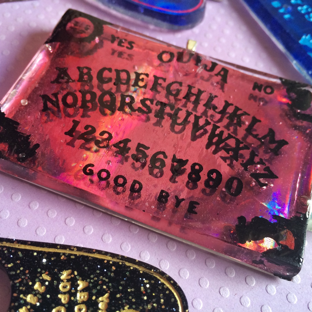 jinxandcurses:  NEW! Holographic ouija boards in planchettes in pink, purple, blue,