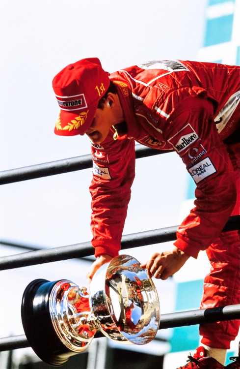 maranello: INTERLAGOS, 2002 — Race winner Michael Schumacher drops the trophy from the podium to his
