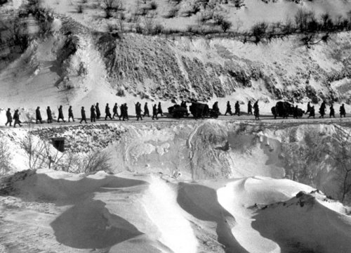 A column of American Marines marches down a canyon road dubbed “Nightmare Alley” during 