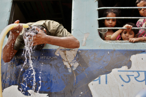 picaet:A commuter poured water over his head as children watched from a train window at a railway st