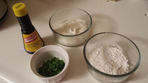 Three bowls, containing flour, chopped parsley, and sour cream, as well as a bottle of Kitchen Bouquet.