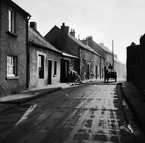 George Pickow. A horse and cart travels along an Irish provincial street at dawn. 1950s