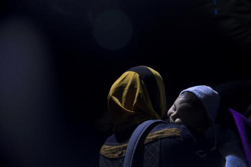 A refugee woman carrying her child waits to cross into Croatia, near Berkasovo, Serbia. (Photo Credi